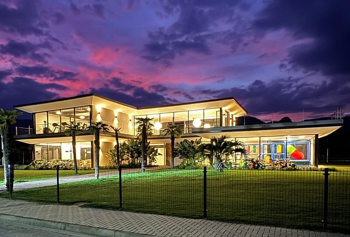 Fachada envidraçada do clube iluminada à noite.