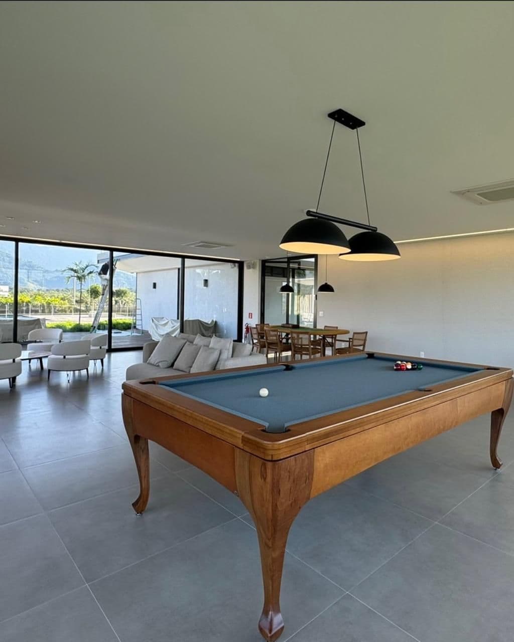 Sala de bilhar com luminárias pendentes e vista para a baía.