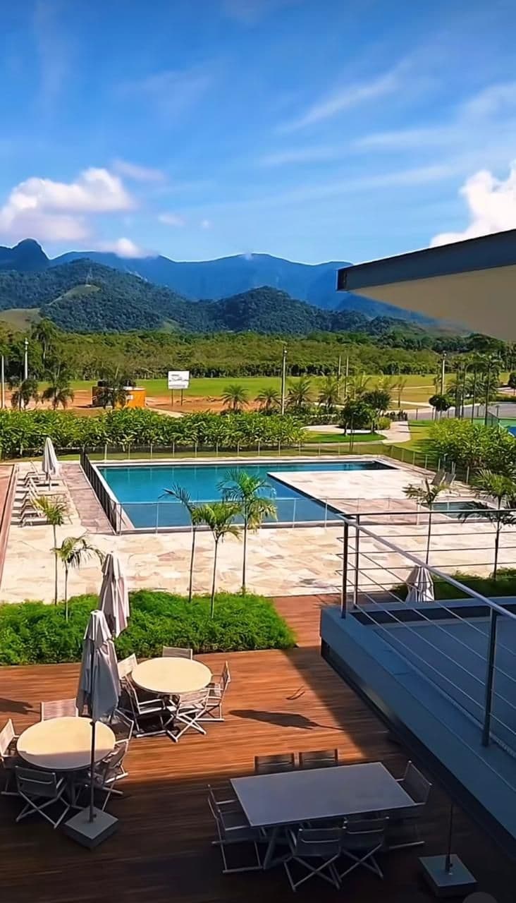 Piscina e deck do clube vistos do alto, com as montanhas ao fundo.